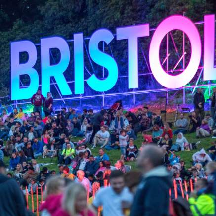 People sitting around a luminous Bristol sign at Bristol International Balloon Fiesta - credit Paul Box