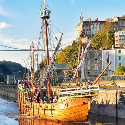 A view of The Matthew replica ship passing through Bristol's Cumberland Basin with the Clifton Suspension Bridge in the background - credit Nick Greville