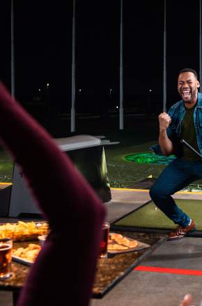 Man pumping fist after golf shot at Topgolf