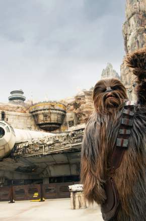 Disney's Hollywood Studios. Chewbacca waving at Star Wars: Galaxy’s Edge, with the Millennium Falcon and towering rock formations in the background.