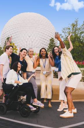 A group of meeting attendees at Epcot pose for a selfie.