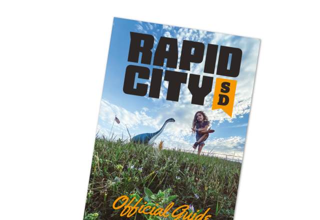 Image of the cover of the Rapid City Official Guide featuring dinosaur park