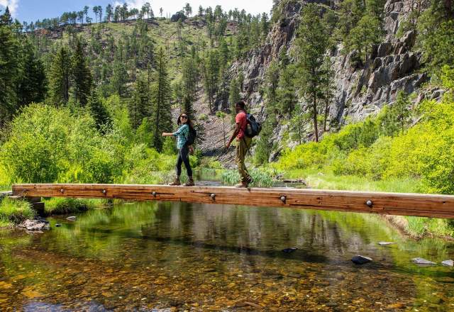 Two hikers cross a bridge on the spring creek portion of the centennial trail in south dakota