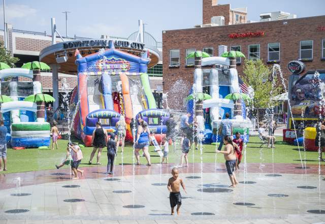 Children running through fountains with bouncy slides in the background