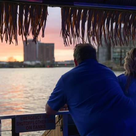 Man and woman looking out over the riverfront at sunset