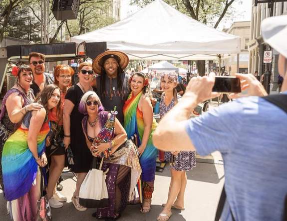 A group of people wearing colorful clothing getting a group photo taken at Ann Arbor Pride