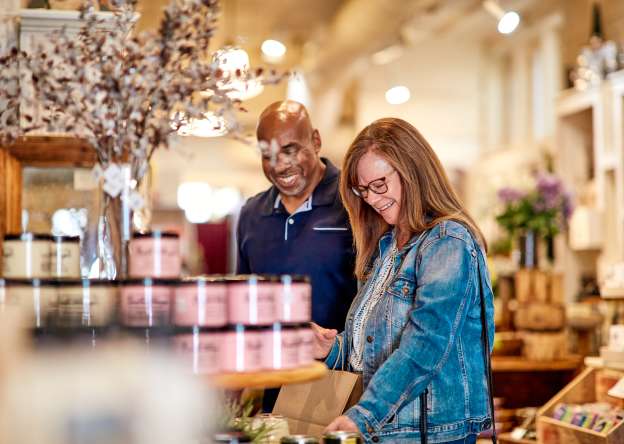 A couple in a shop looking at candles, both are smiling.