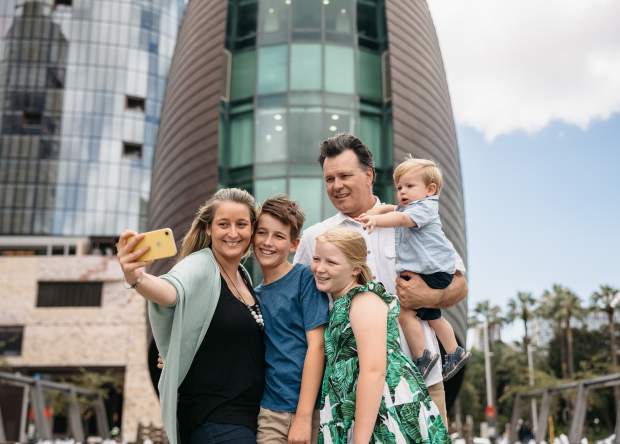 A family pose for a photo in front of The Bell Tower in Perth City
