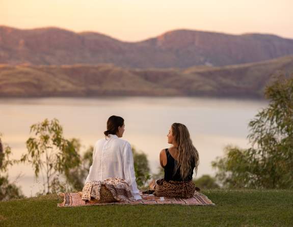 Two people picnicing at sunset at Discovery Resorts - Lake Argyle