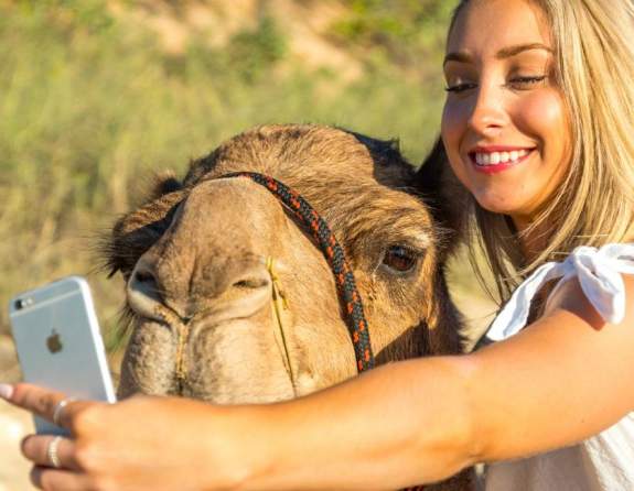 Woman taking selfie with a camel