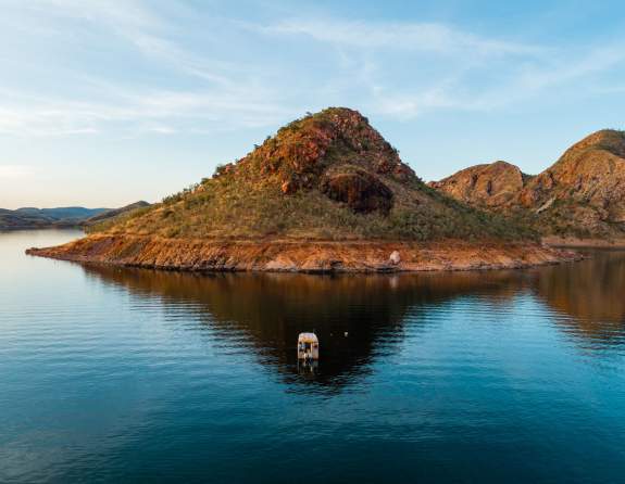 A Lake Argyle Cruises boat shown on the lake in front of one of the lake's islands