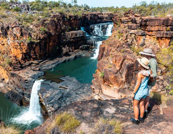 Hikers stand at the lookout point for Punamii-Unpuu (Mitchell Falls) with a view of three tiers of the falls