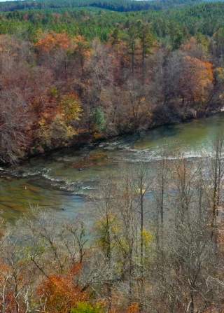 An aerial shot of Cahaba River Park shows fall foliage over the free flowing Cahaba River.