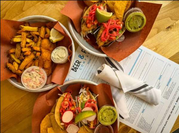 Overhead view of menu, silverware, Baja tacos, and fish and chips at Beer & Fish.