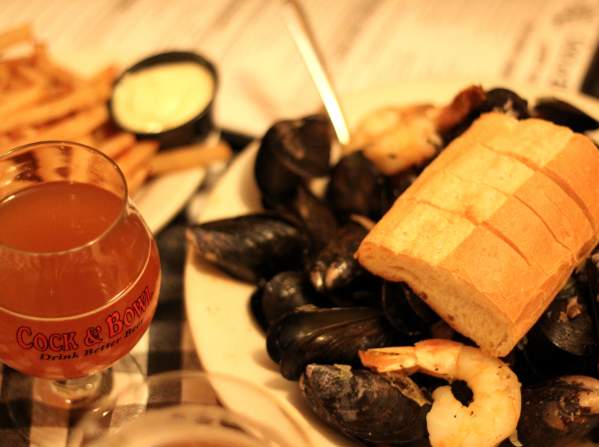 a beverage with a plate of french fries, as well as a plate of mussels with a piece of shrimp and bread on top