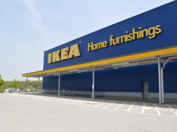 a blue building with "IKEA Home furnishings" written in yellow on the side of the building with an empty parking lot