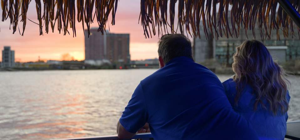 Man and woman looking out over the riverfront at sunset
