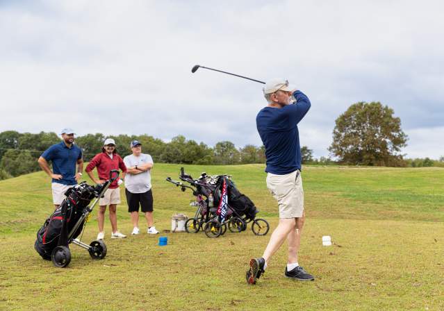 Man swinging at the golf course.