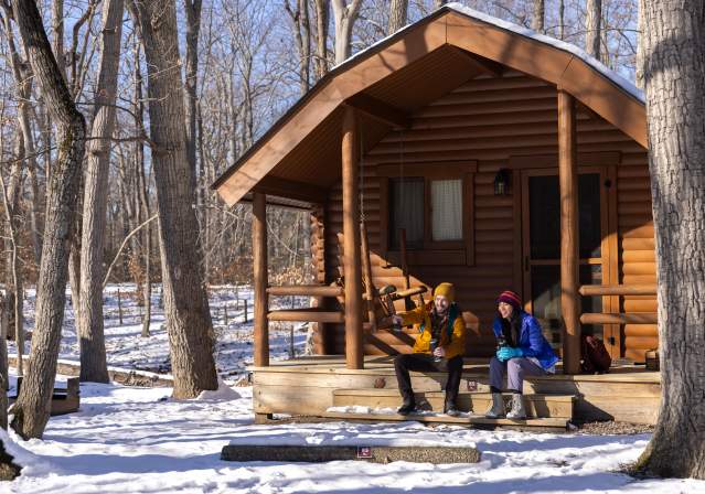Couple sitting in front of a cabin.