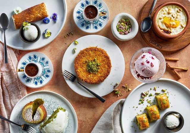 A vibrant spread of traditional desserts, including baklava, ice cream, and sweet pastries, arranged on decorative plates with garnishes.