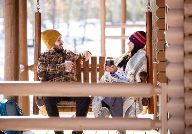 Couple Facing Eachother on an Outdoor Bench with Warm Drinks