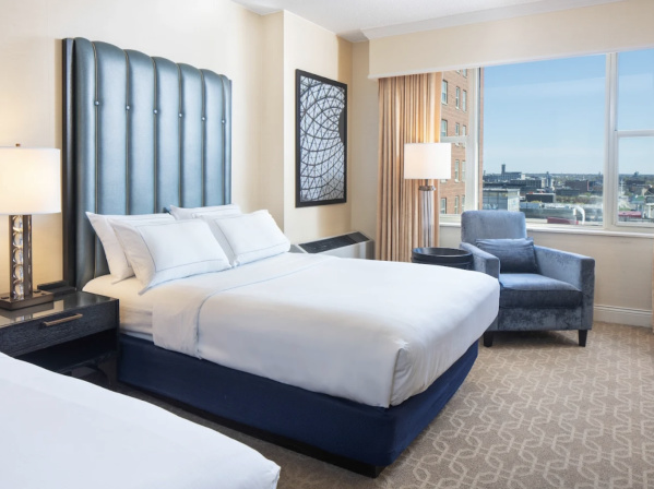 a modern hotel room with a bed and a chair by a window