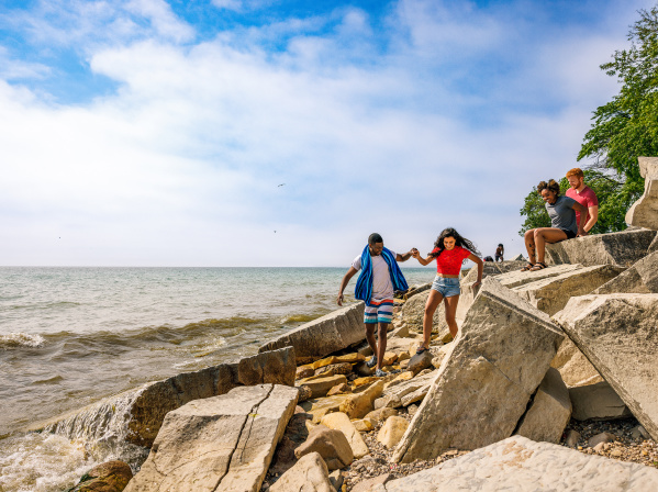 friends climb on beach rocks on the lakefront