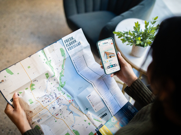 A person holding an official visitors map of Milwaukee with a Map King App open.