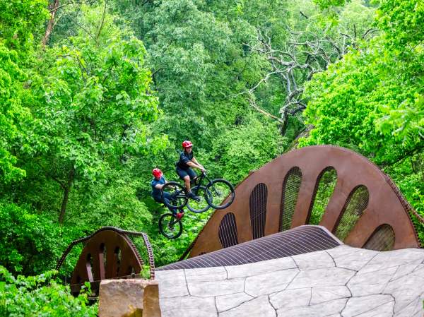 Two cyclists catch air on a bike jump feature in Bentonville.