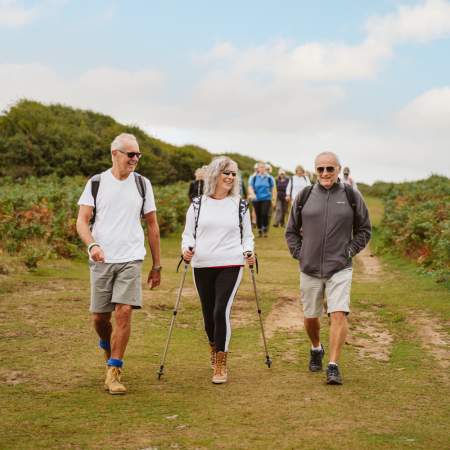 group of older people chatting and hiking along gower with hiking equipment