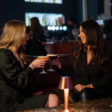Two women sharing cocktails in a bar