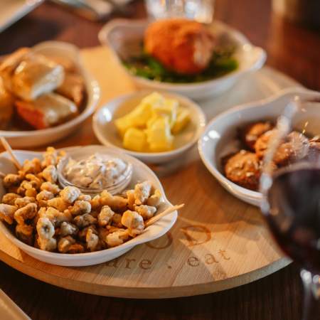 Battered cockles in a bowl with a glass of red wine.