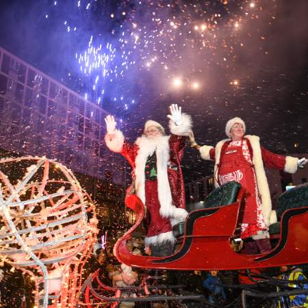 Father Christmas and Mrs Claus waving from their sleigh while fireworks go off in the swansea christmas parade