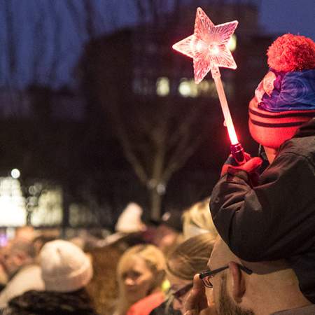 A young boy holding a star wand at the Christmas Parade
