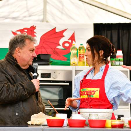 A man interviewing a woman chef in front of a Welsh flag