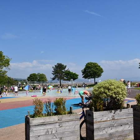 families playing in the water in the summer sun at blackpill lido