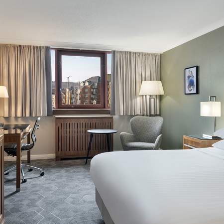 A contemporary hotel room with a bed, desk and TV.