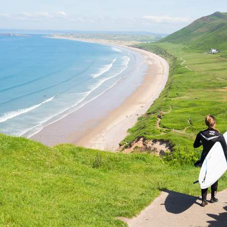 Surfer walking down to Rhossili Bay Beach