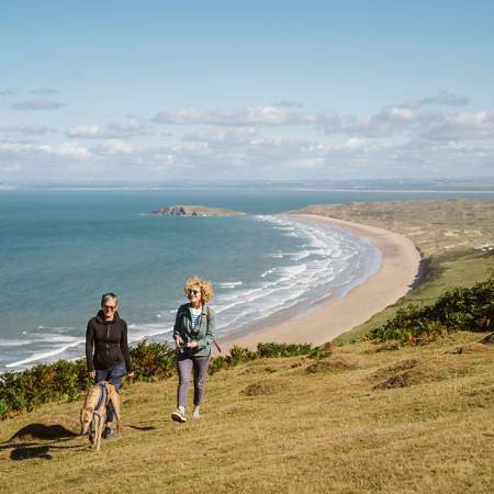 Two women walking a dog at Rhossili.