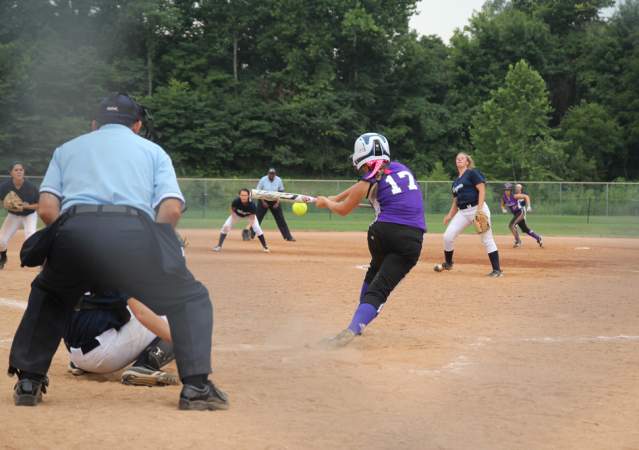 A batter hitting a softball during a game