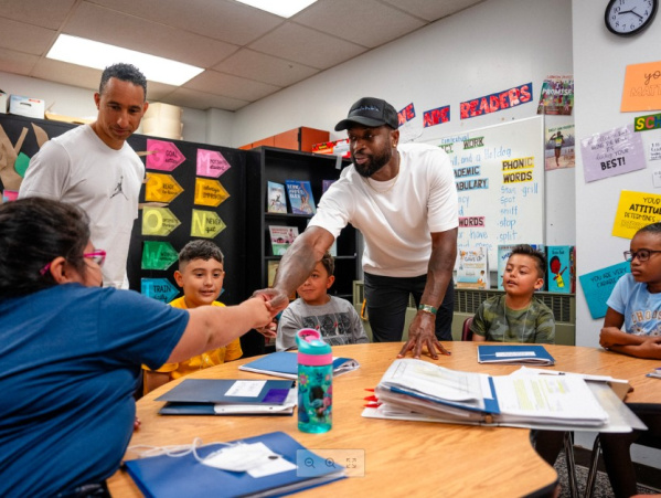 Shaka & Wade in a school classroom shaking hands with a student at a table