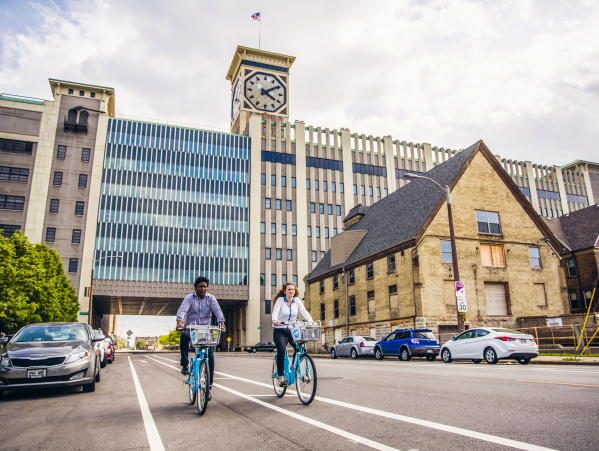 two people using bublr bikes, biking under the clocktower