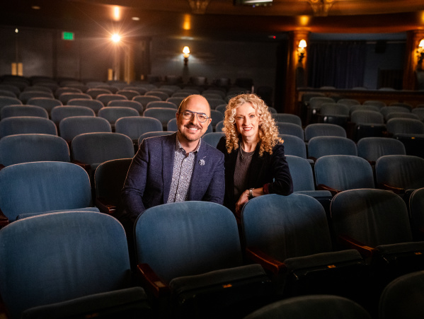 David Caruso and Susan Varella sit smiling in blue theater chairs