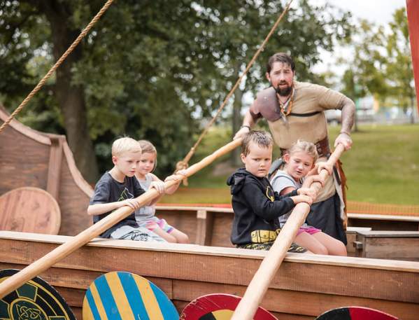 Kids rowing a Viking shop replica with a man dressed in period costume at the Dublin Irish Festival