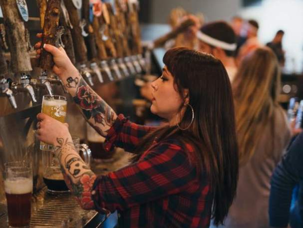 female bartender pouring beer into a glass at Mad Tree bar