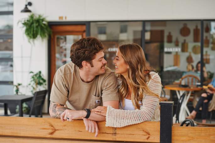 a man and woman look at each other in front of a cafe