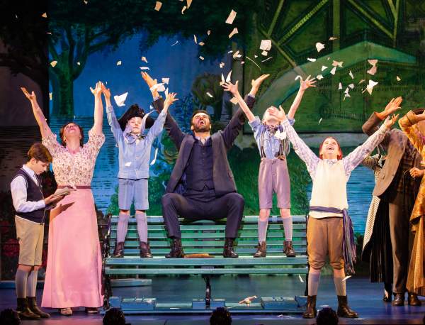 theatre stage with cast raising arms into air