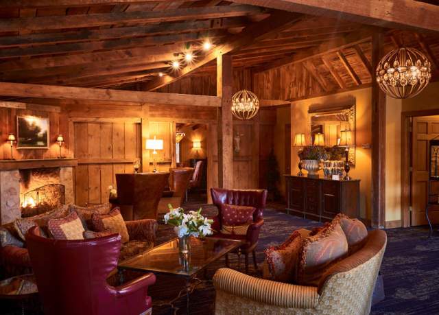Interior of a hotel room with wood paneling and a sitting area and fireplace