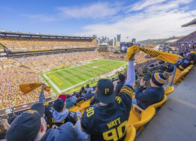 People in the stands of a football stadium waving yellow towels