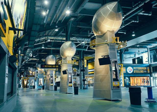 Large steel footballs on stands in Acrisure stadium in Pittsburgh. Signage around the hall reads Pittsburgh Steelers